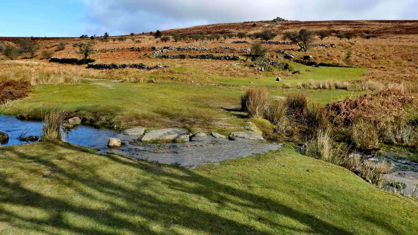 Over Rex’s Bridge to the ruins of the miners’ house with the garden enclosures behind it. The ruins of the mine captain’s house are visible near the far right in the bracken